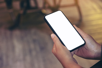 Mockup image of a hand holding black mobile phone with blank white desktop screen