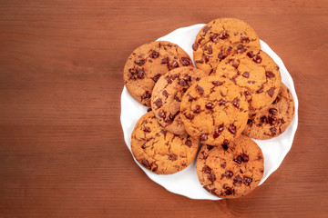 Chocolate chip cookies, shot from the top on a dark rustic wooden background with a place for text