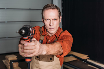 middle aged repairman holding directional screwdriver in front of him in garage