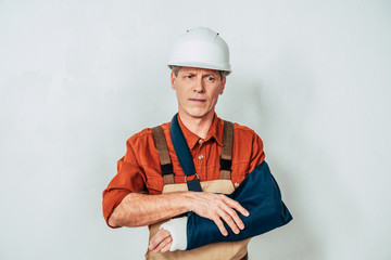 repairman with bandage standing and holding arm on white background