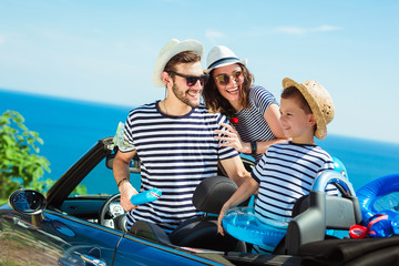 Fototapeta na wymiar Happy family travel by car to the sea. People having fun in cabriolet. Summer vacation concept