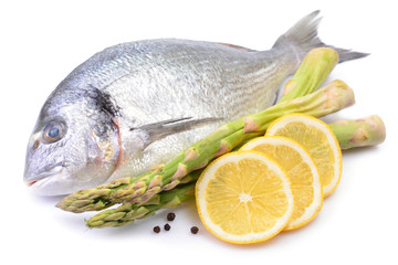 Dorado fish on white background with asparagus and lemon