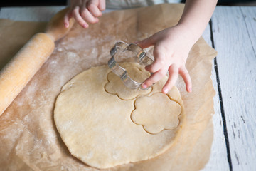 Children hands cutting flower cookies