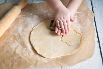 Children hands cutting flower cookies