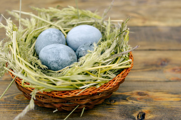 Easter eggs in green nest on wooden table.