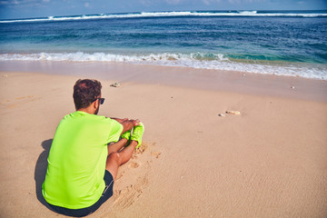 Sportsman stretching on a exotic tropical beach after jogging / exercising.