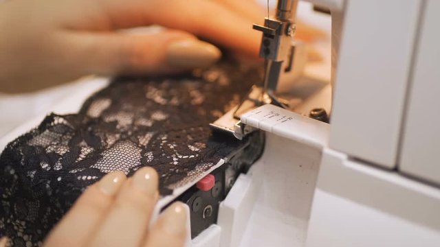 Professional tailor, seamstress using overlocking sewing machine.