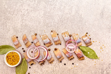 Pieces of pickled Norwegian salted herring with spices and onions. Marinated fish on a stone...
