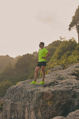 Sportsman making pause after workout on a tropical cliff.