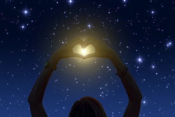 Silhouette of a girl holding heart-shape symbol for love on a starry night sky. My astronomy work.