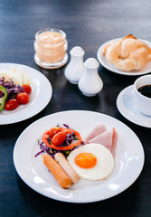 eggs, sausage, ham, salad American breakfast with black coffee.