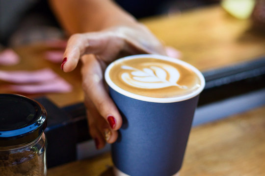 Servieren eines Cappuccinos im blauen Pappbecher