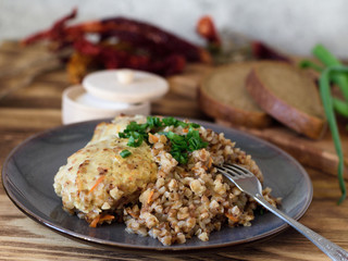 Buckwheat porridge with meatballs urashennaya greens on a plate with a fork on a wooden background