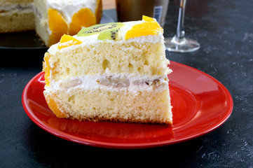 Big piece fruit sponge cake on a black background.  Festive cake.