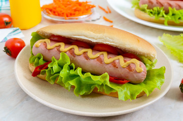 Tasty hot dogs with sausage grill, ketchup, mustard, lettuce, tomatoes on a plate. Close up