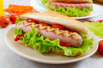 Tasty hot dogs with sausage grill, ketchup, mustard, lettuce, tomatoes on a plate. Close up