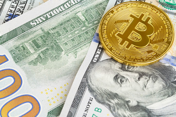 Two coins of bitcoin on banknotes of one hundred dollars. Exchange bitcoin cash for a dollar.