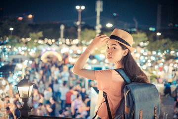 Portrait asian woman tourist backpacker and hat stand watch the night market with so many people...