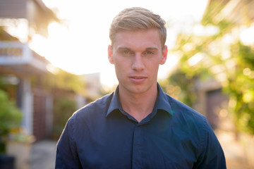 Face of young handsome businessman with blond hair outdoors