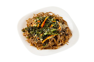 Closeup plate of buckwheat noodles with vegetables salad isolated at white background.