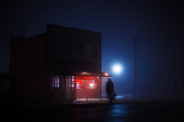 Night blue misty landscape. A small shop with a red illuminated signboard stands on the side of the...