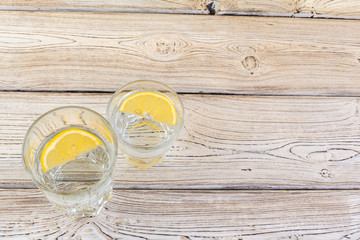 Glass with water and lemon on wooden table
