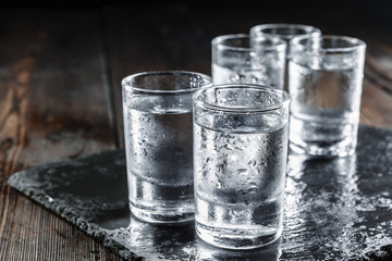 Vodka in shot glasses on rustic wood background - obrazy, fototapety, plakaty