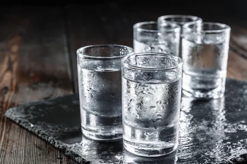Foto op Plexiglas Wodka in borrelglaasjes op rustieke houten achtergrond © NewFabrika