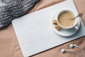 Cup of tea with milk, brown anise sugar and a Notepad. Tray on the bedspread. Space for text and production.