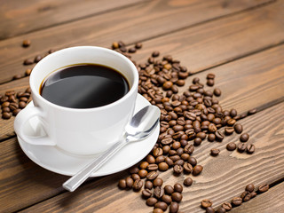 Coffee cup, beans and spoon on wooden background on the table. Perfect breakfast in the morning. Rustic style