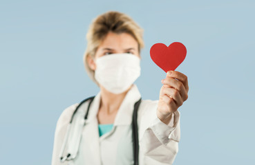 beautiful girl doctor with a red heart in her hands on a blue isolated background.Concept of love