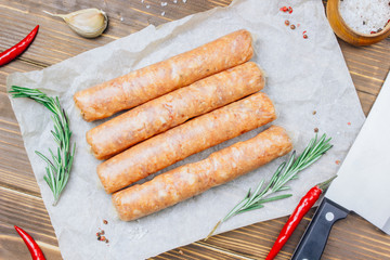 Raw Tyrolean sausages with rosemary over wooden background