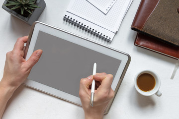 Digital tablet computer with isolated screen in female hands against the background of a cafe - table, smartphone, cup of coffee