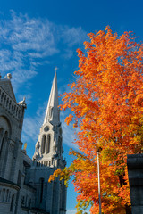 Exterior view of the Basilica of Sainte-Anne-de-Beaupre church with red maple tree
