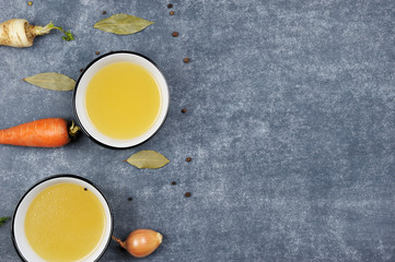 Homemade broth in the bowls on the  grey background.