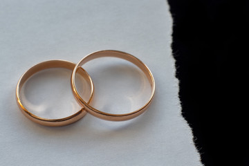 wedding rings on white paper and black background.