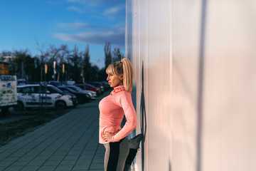 Sporty blonde woman resting from running on the street in the dusk.