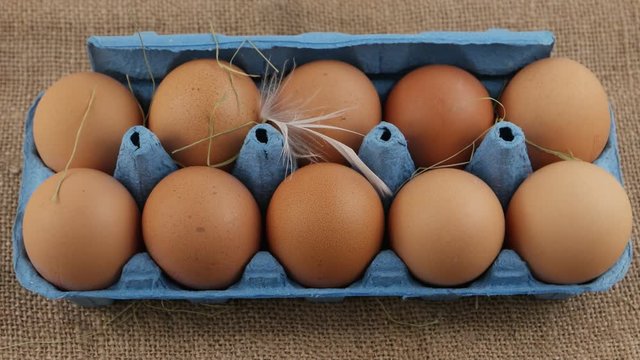 Ten eggs in a blue ecological packaging are on a piece of burlap