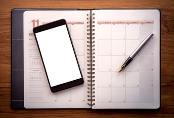 Mock up phone on weekly planner notebook.