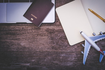 Mock up image of passport,laptop,notebook and plane isolated on old wooden table background.
