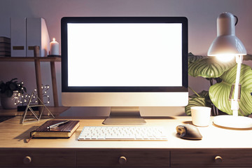 Stylish scandinavian interior of home creative desk by night with mock up computer screen, plants, office accessories and notes. Minimalistic space for work, hobby and listen music. Freelancer space.