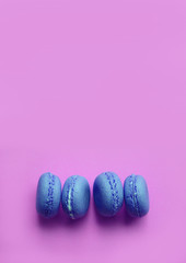 Four blue macaroons on the side on a pink background.