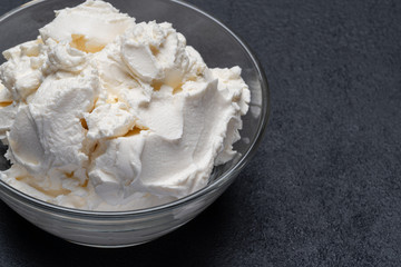 Traditional Mascarpone cheese in glass bowl on concrete background