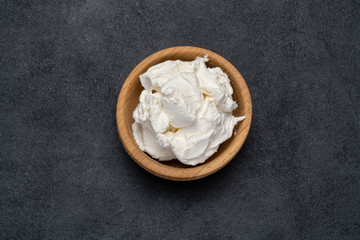 Traditional Mascarpone cheese in wooden bowl on concrete background