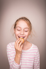 Happy blond caucasian child girl eating cookie.