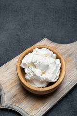 Traditional Mascarpone cheese in wooden bowl on concrete background