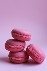 Obraz na płótnie Canvas Four pink macaroons on a light pink background, sweet minimal food concept