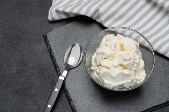 Traditional Mascarpone cheese in glass bowl on concrete background