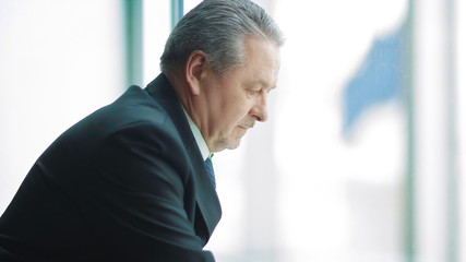 businessman signs a document, standing near the office window