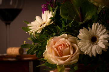 Old vase of ceramic with flowers and glass of wine in the background
